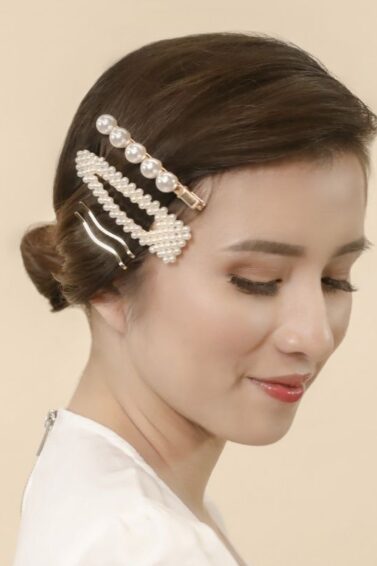 Asian woman with hair in a low bun and wearing hair clips on one side of her hair