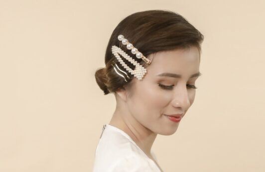 Asian woman with hair in a low bun and wearing hair clips on one side of her hair