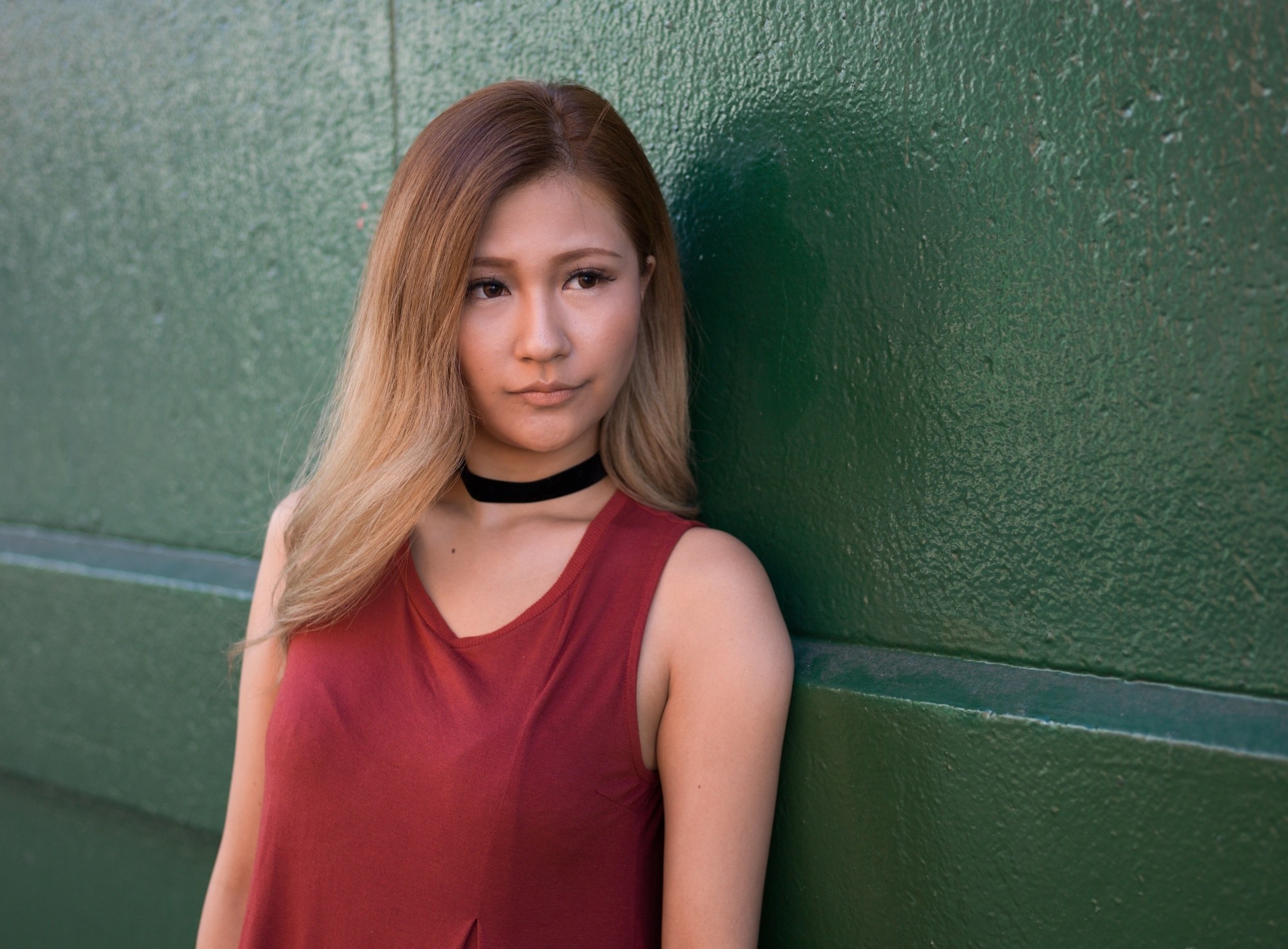 Asian woman with dark copper blonde ombre hair wearing a red sleeveless top