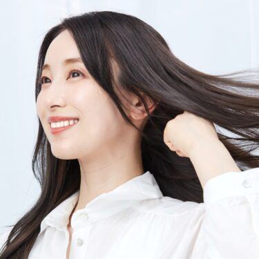 Asian woman touching her long hair wearing a white long-sleeved polo