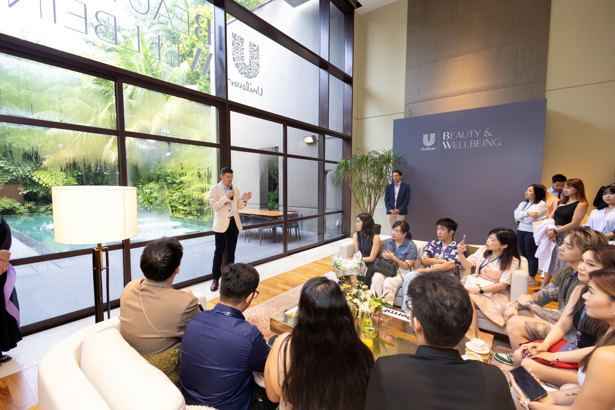 Asian guests in a house listening to a male speaker at a hair care event