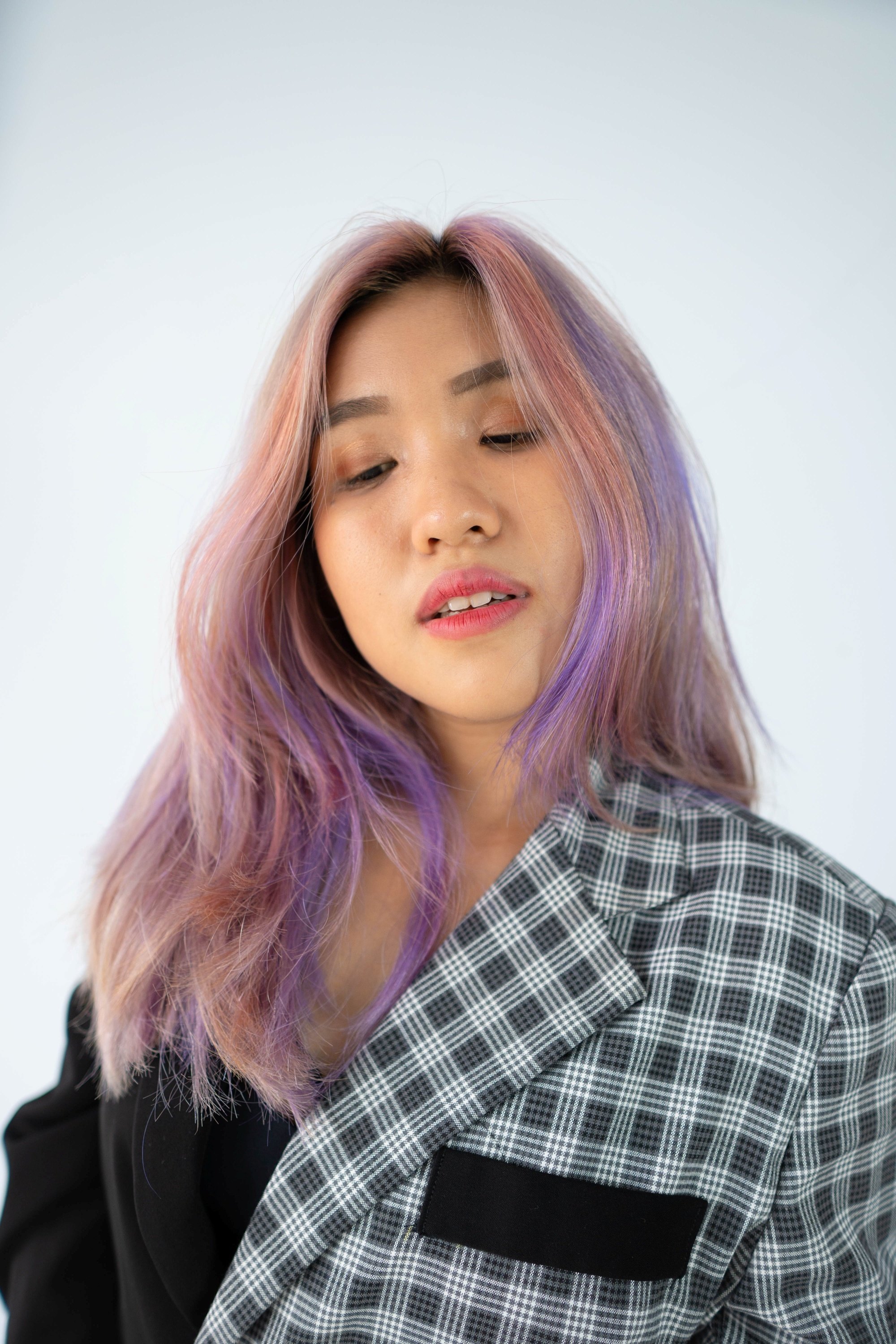 Woman with long, ashy unicorn layered hair wearing a checkered polo