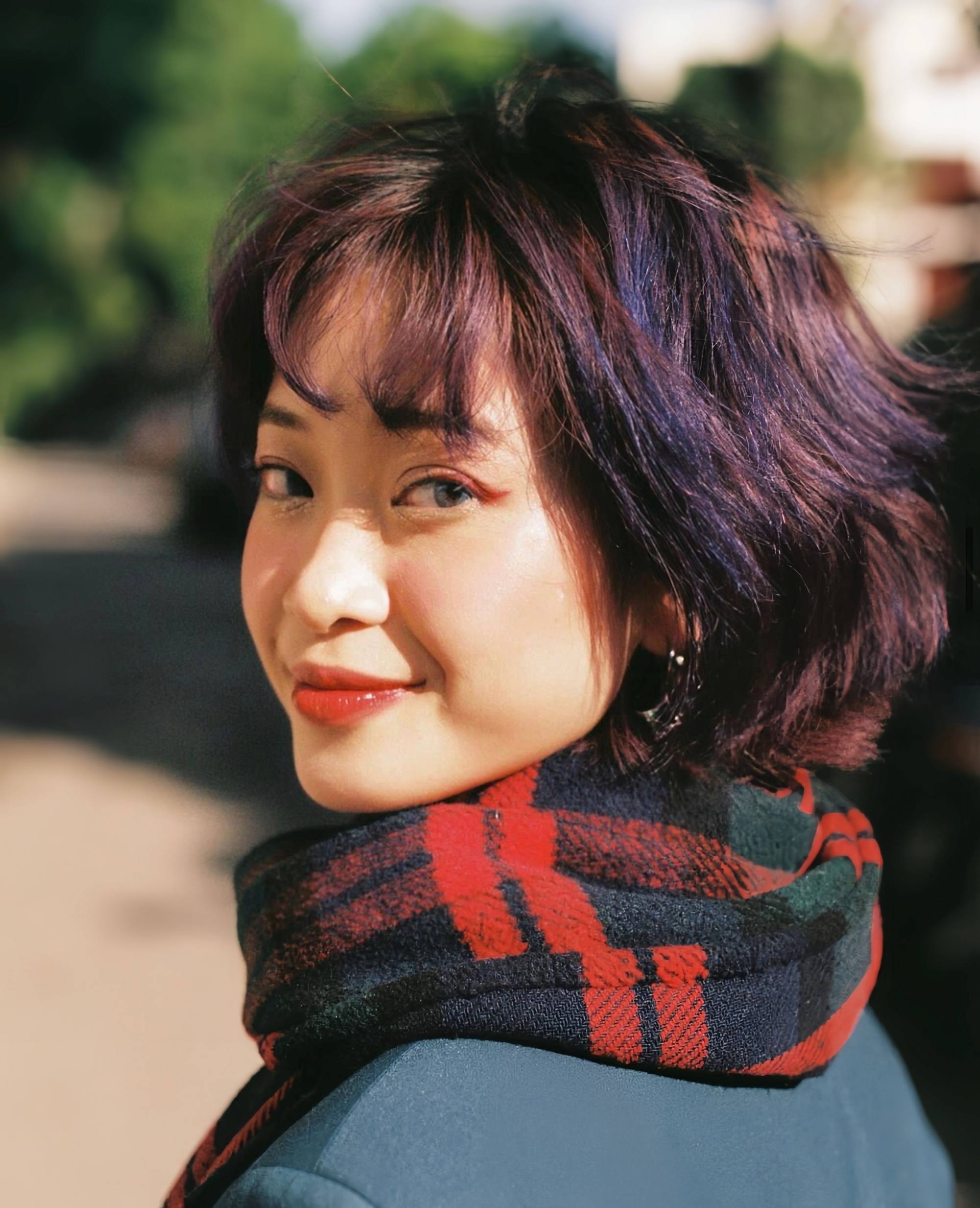 Asian woman with a wavy shag haircut wearing a scarf