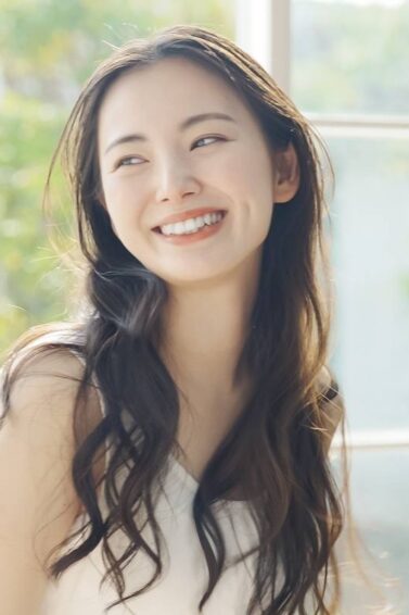 Asian woman with long wavy hair smiling posing for a dead hair treatment concept