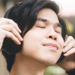 Asian man with an emo hairstyle listening to music with headphones