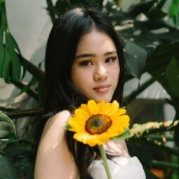Asian woman holding a sunflower and posing for a photo shoot about sunflower oil benefits for hair