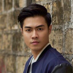 Asian man with a side part haircut wearing a dark blue jacket.