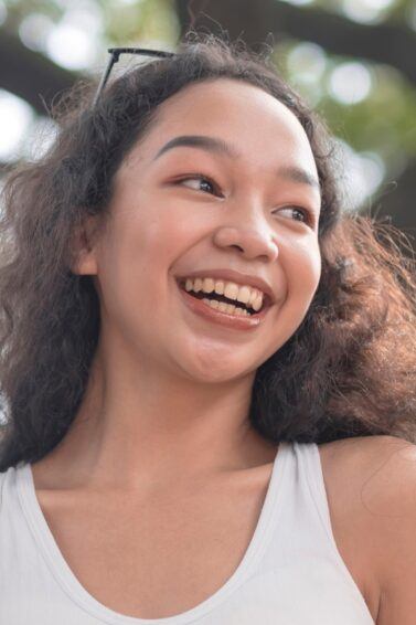 Filipino woman with long curly hair smiling.