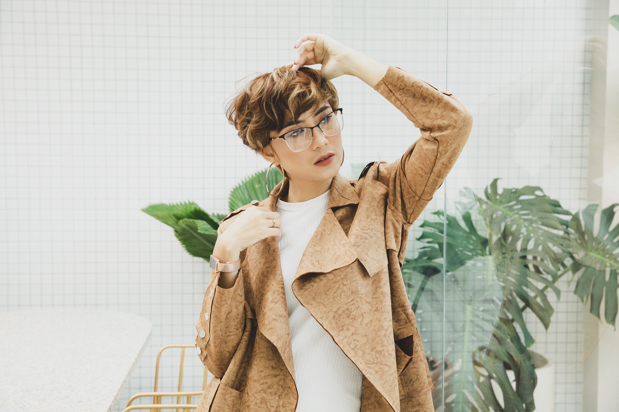 Asian woman with brown short hair with dark blonde highlights wearing a brown coat.