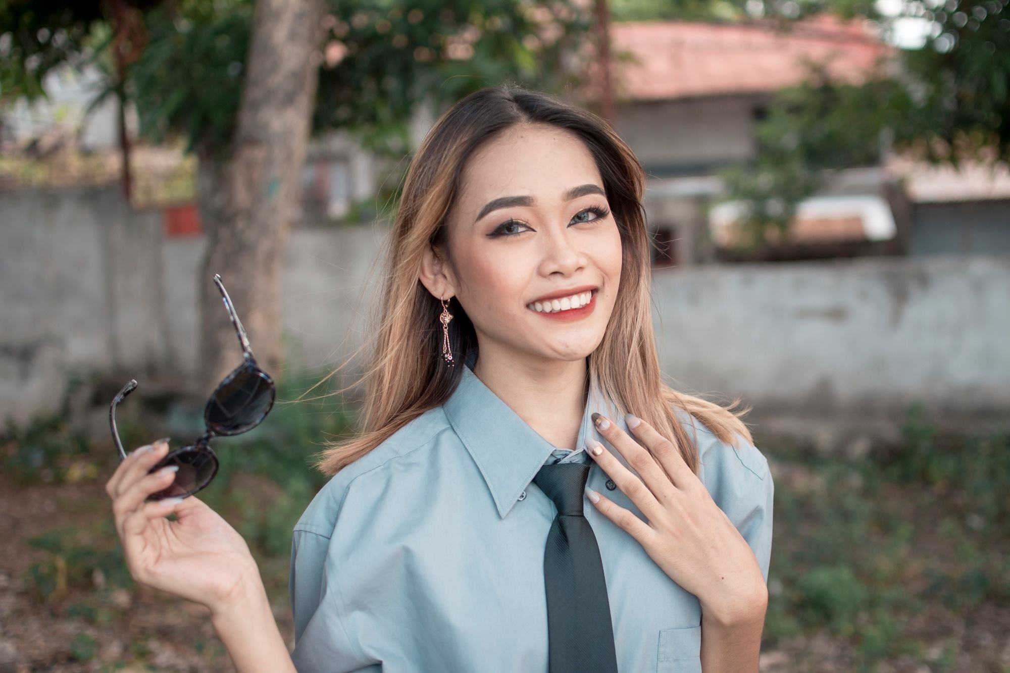Asian woman with dark blonde hair color wearing a collared blouse and a neck tie.