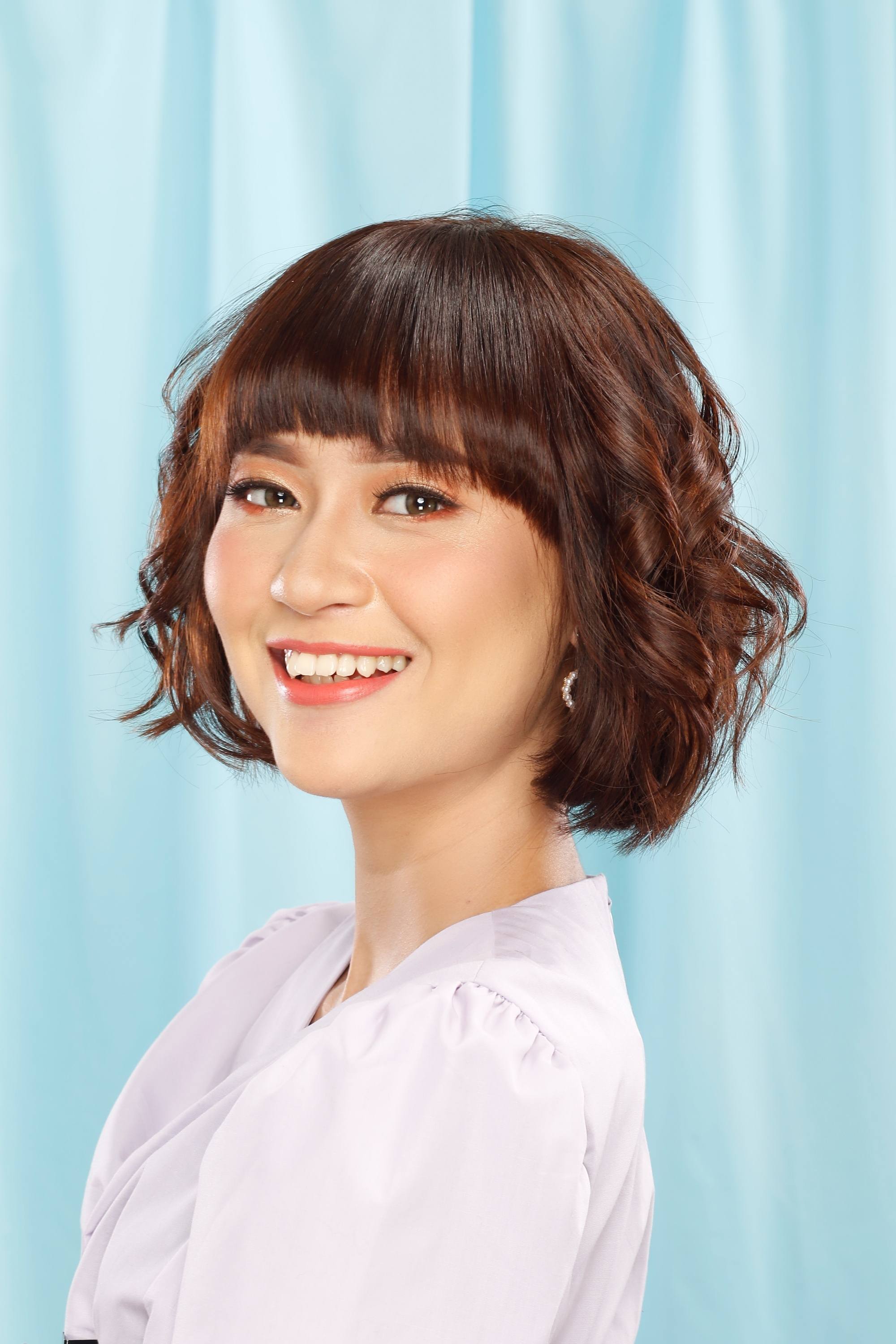 Asian woman with dark short hair with chestnut brown highlights.