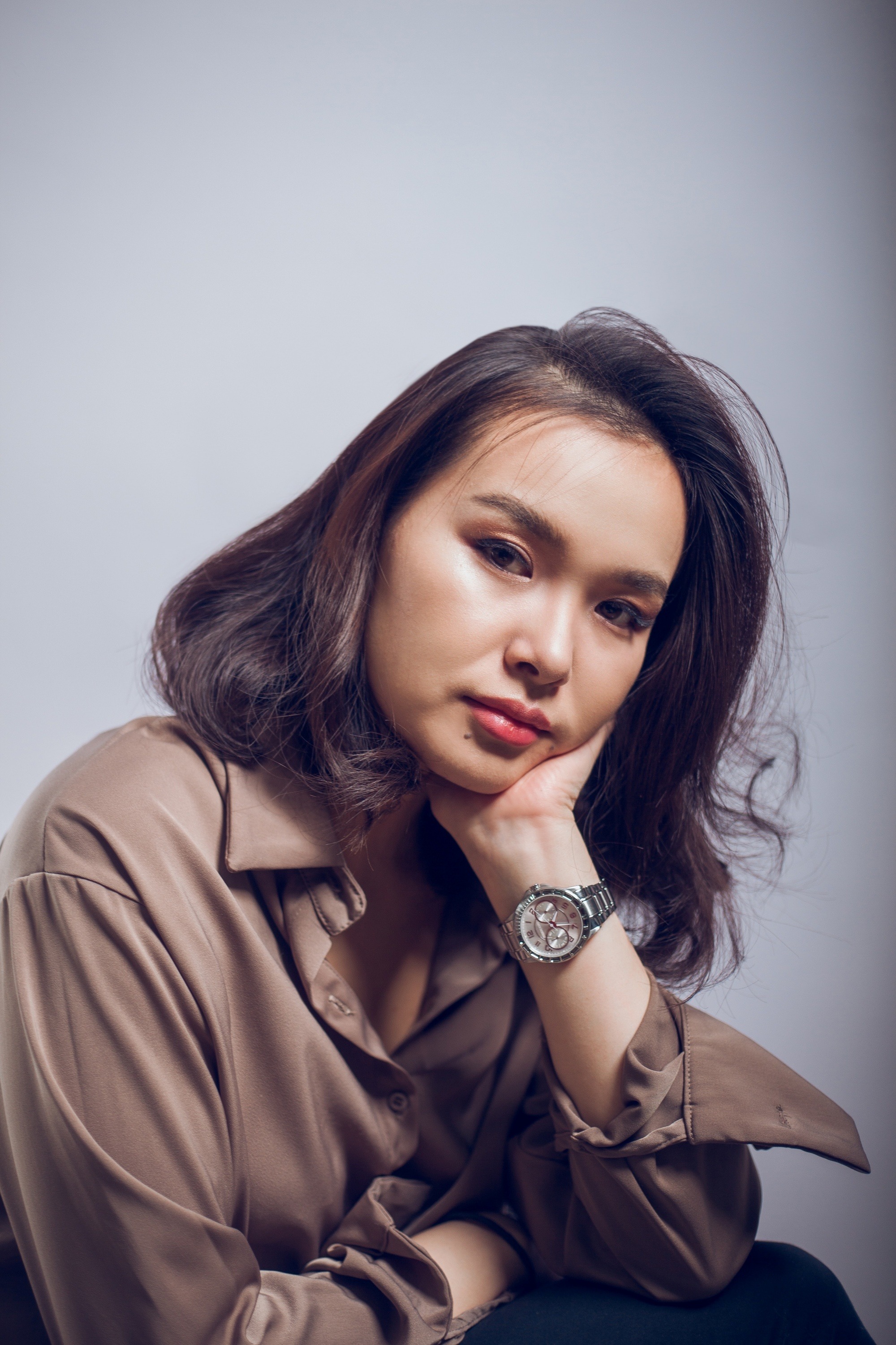 Asian woman with dark hair wearing a brown polo.