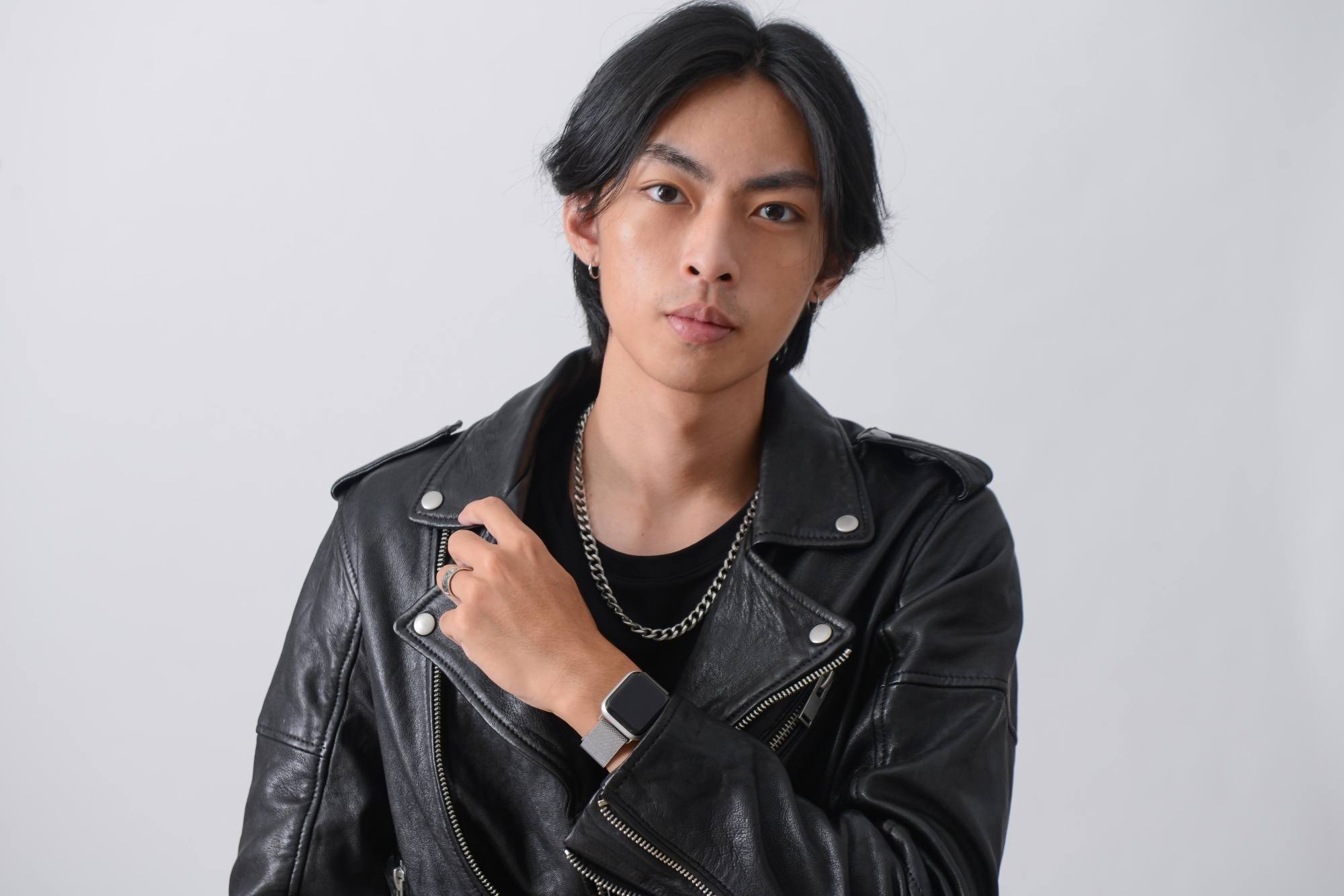 Asian man with a curtain hairstyle wearing a black leather jacket.
