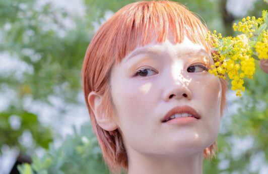 Asian woman with short strawberry blonde hair.