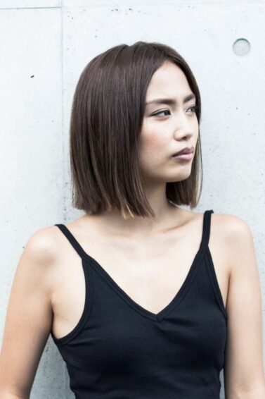 Asian woman flaunting a new hairstyle wearing a black tank top.