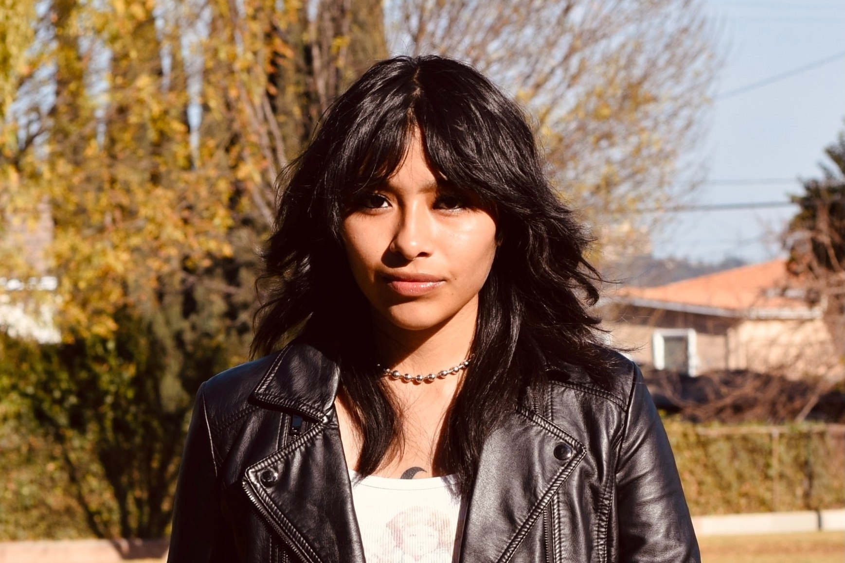 Woman with wolf cut hair wearing a black leather jacket.