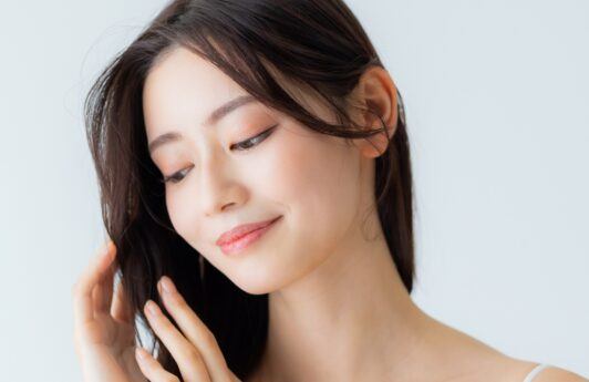 Asian woman touching her hair and posing for a hair care routine concept.