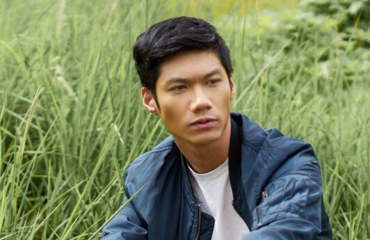 Asian man with a crew cut wearing a blue jacket.