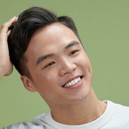 Asian man touching her hair to show his hairstyle for men with round faces.
