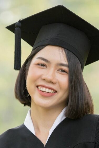 Asian woman with a short, graduation hairstyle wearing graduation attire.