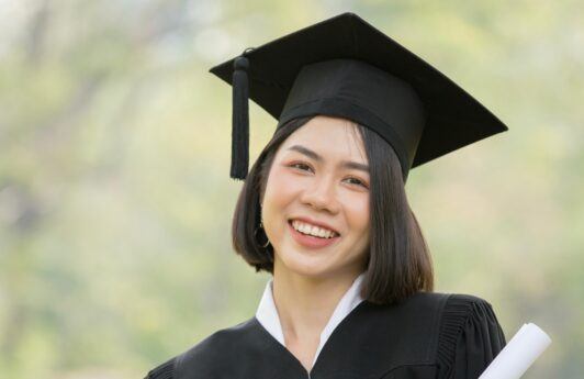 Asian woman with a short, graduation hairstyle wearing graduation attire.